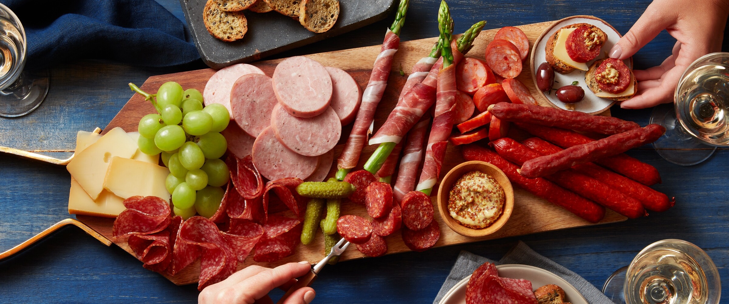 Charcuterie board covered with meat, cheese, crackers and spreads.